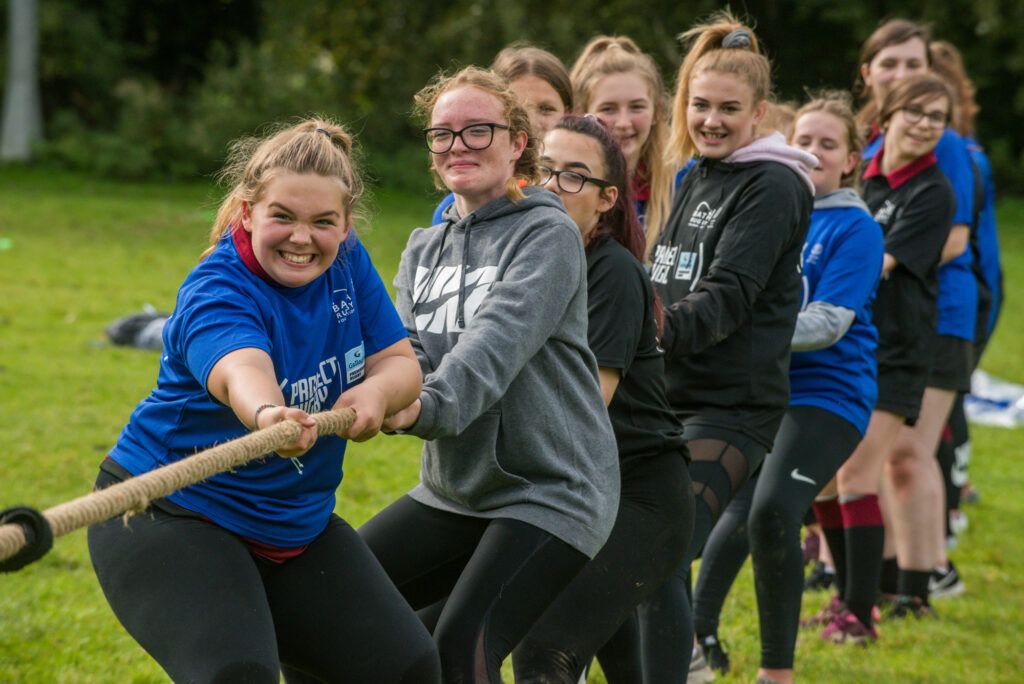 Bath Rugby Foundation volunteers and young women playing tug of war