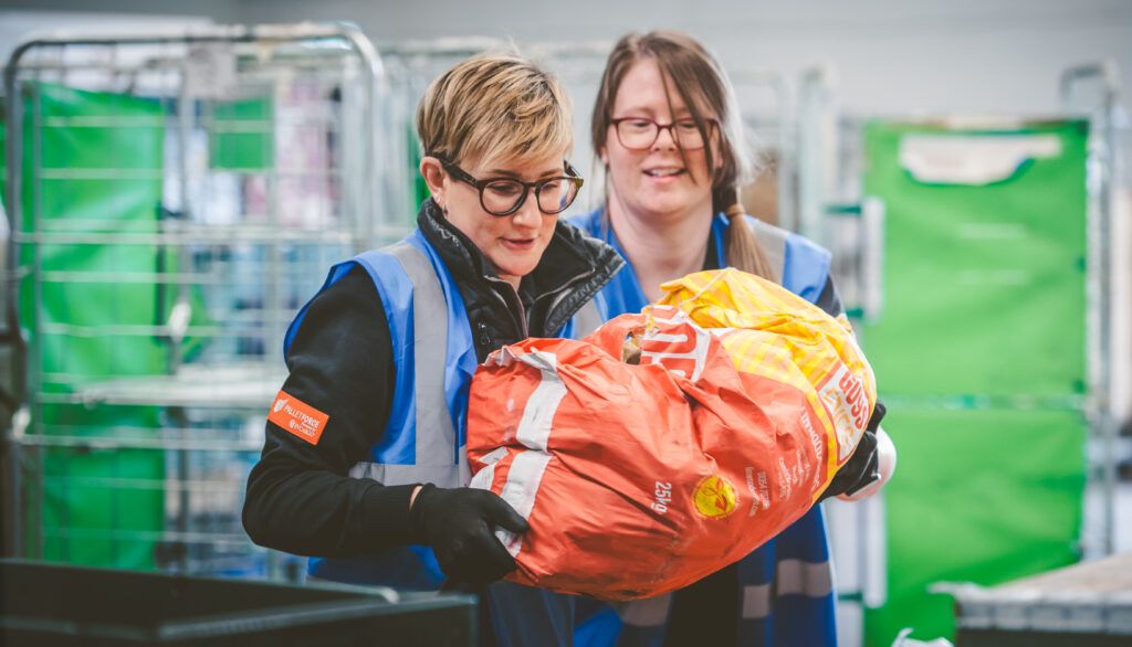 Two members of FareShare Midlands carrying sack of potatoes