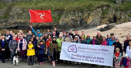 supporters gathered on the coast holding a flag and a banner supporting Diana Princess of Wales Trust.