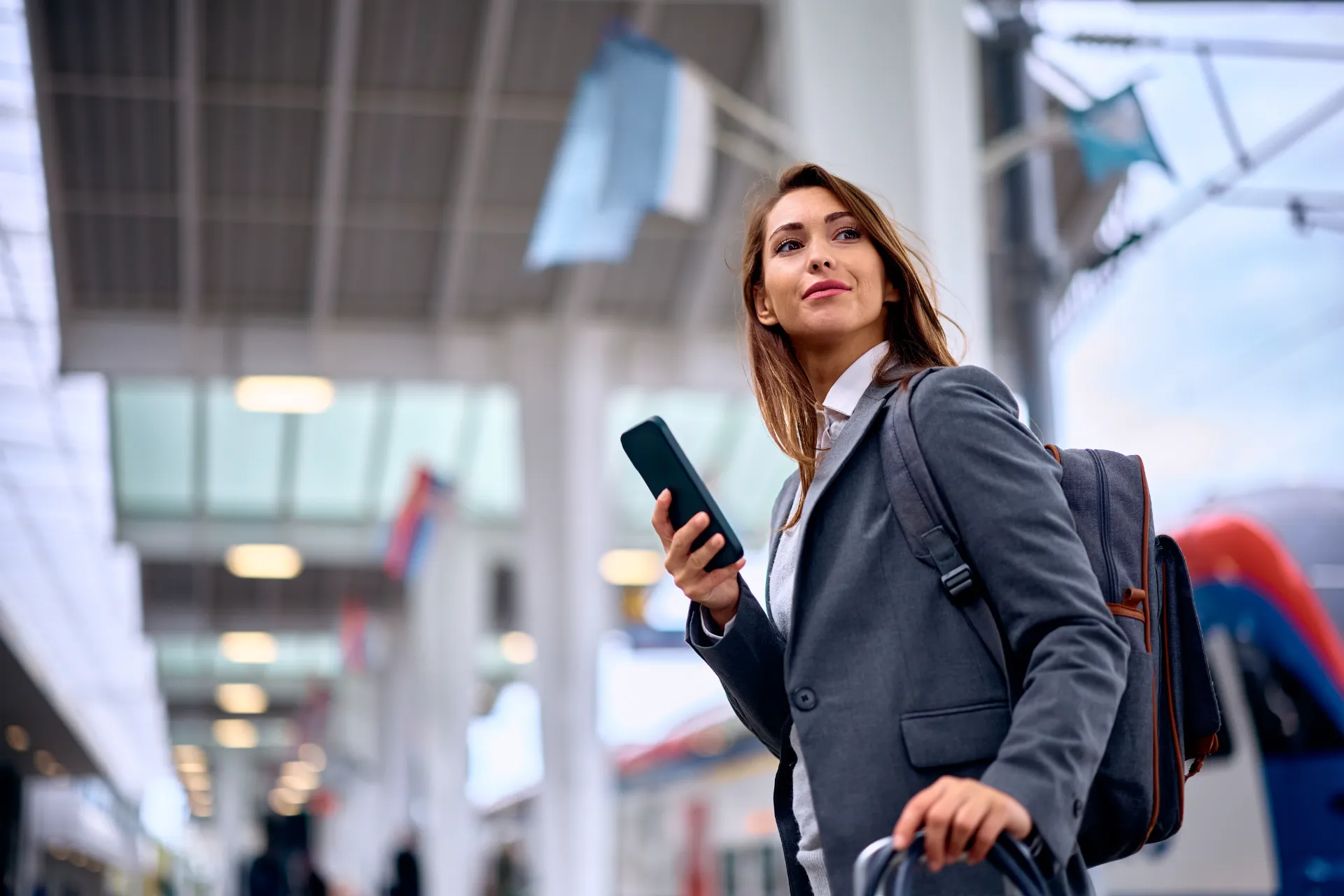 Young businesswoman using smart phone while arriving at train station.